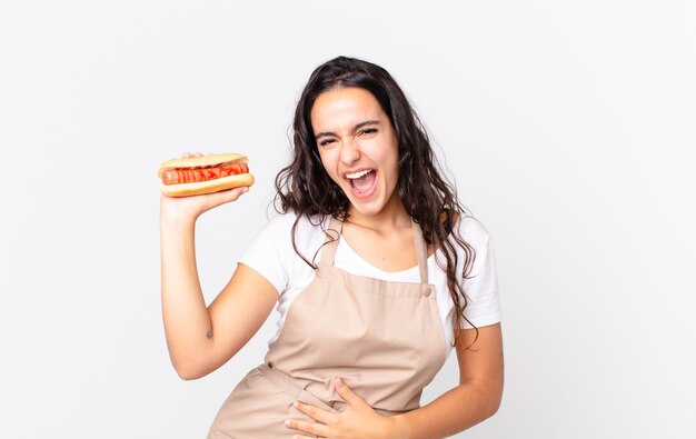 Chef bonita hispana mujer sosteniendo un hot dog