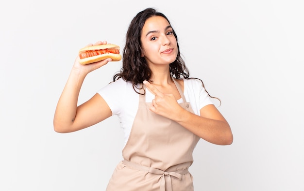 Chef bonita hispana mujer sosteniendo un hot dog