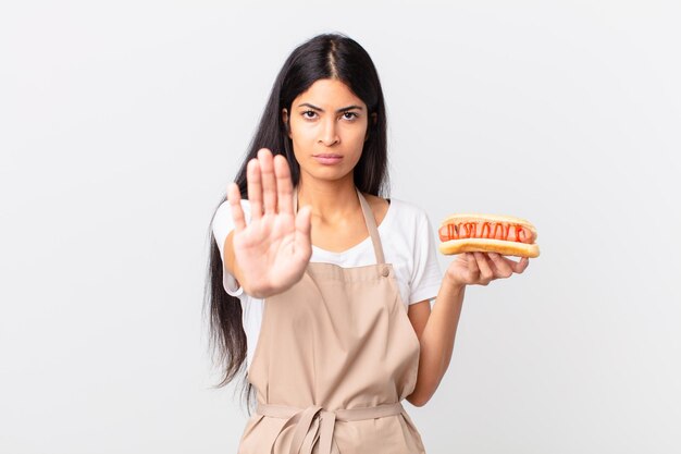 Chef bonita hispana mujer sosteniendo un hot dog