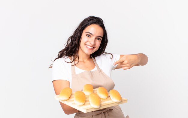 Chef bonita hispana mujer sosteniendo un pan bollos troy