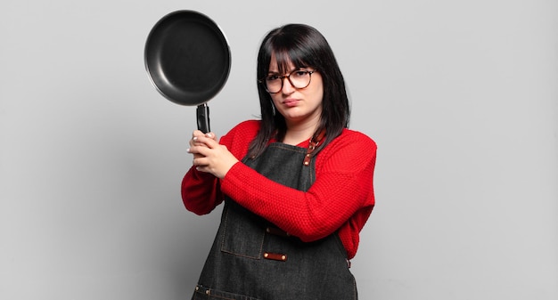 Chef bonita mulher de tamanho grande cozinhando com uma panela