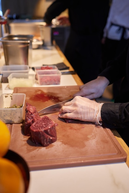 Chef carnicero cortando carne de cerdo con cuchillo en la cocina cocinando comida