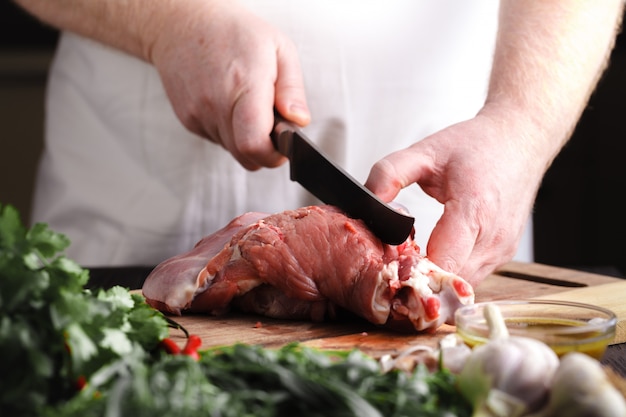 Chef carnicero cortando carne de cordero con cuchillo