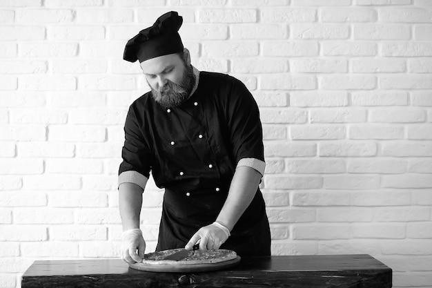 Chef chef barbudo prepara comidas en la mesa de la cocina