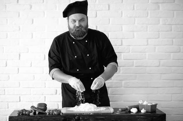 Chef chef barbudo prepara comidas en la mesa de la cocina