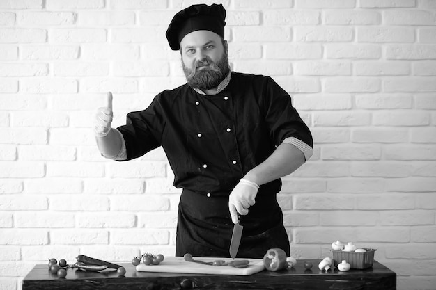 Chef chef barbudo prepara refeições na mesa da cozinha