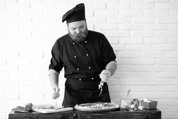 Chef chef barbudo prepara refeições na mesa da cozinha