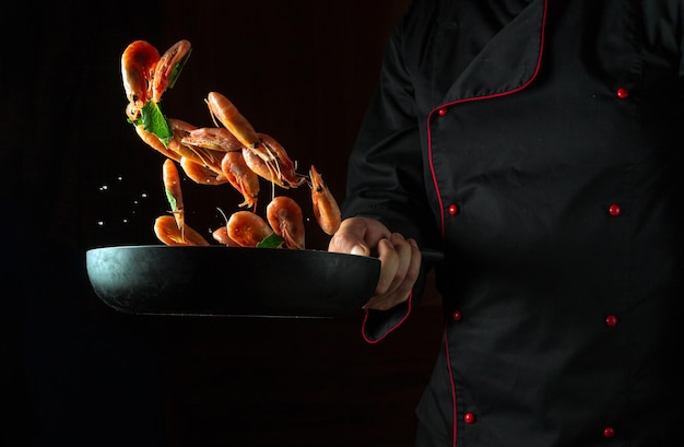 Foto el chef cocina camarones en una sartén con perejil cocinar mariscos o comida vegetariana saludable y comida sobre fondo negro congelar en movimiento espacio publicitario gratuito