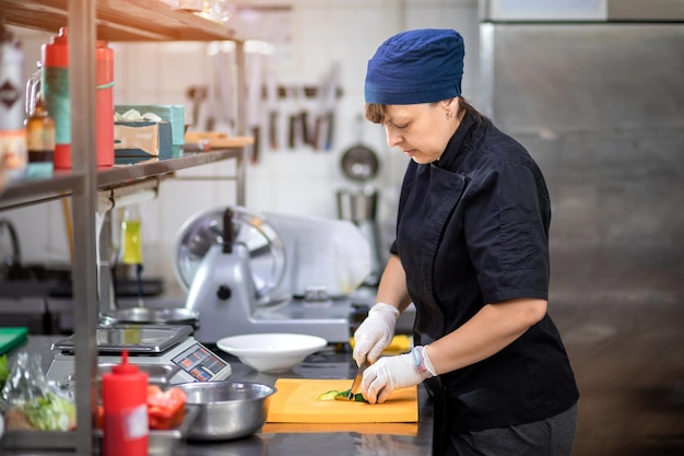 El chef de la cocina corta un pepino y prepara una ensalada griega Concepto de ensalada vegetariana