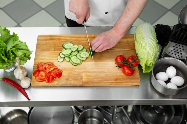 Chef en la cocina corta verduras frescas y deliciosas para una ensalada de verduras