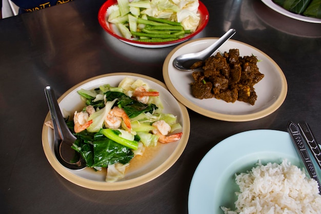 Chef cocina fusión de comida callejera cocina local tradicional del sur de Tailandia con arroz en un plato para que los clientes tailandeses servidos coman una bebida en la mesa en la tienda del restaurante en Bangkok Tailandia