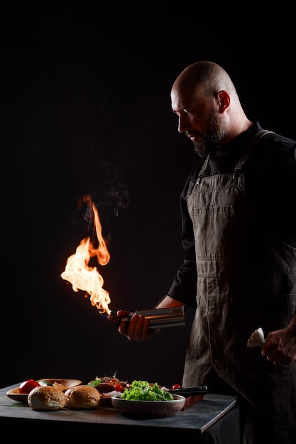 Foto el chef cocina hamburguesas, asa albóndigas a fuego abierto