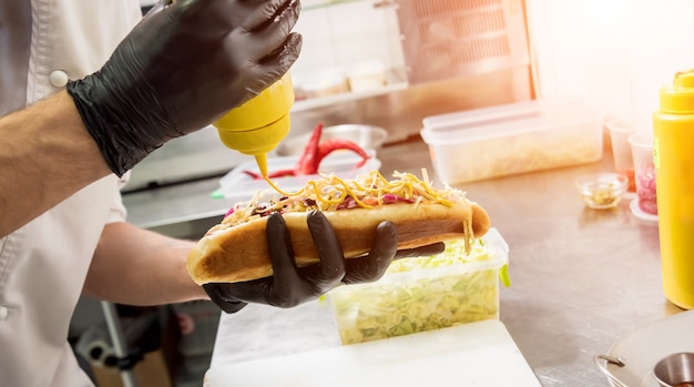El chef cocina hot dog en una parrilla.