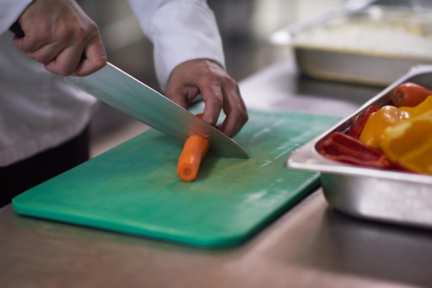 chef en la cocina del hotel cortar verduras con cuchillo y preparar comida