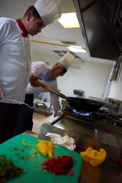chef en la cocina del hotel prepara comida vegetal con fuego