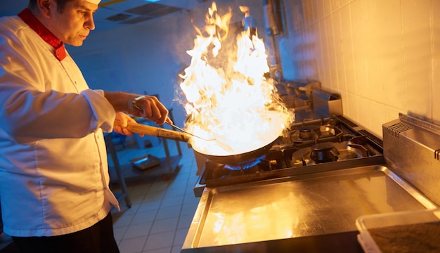 chef en la cocina del hotel prepara comida vegetal con fuego