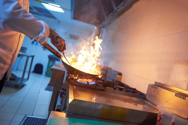 chef en la cocina del hotel prepara comida vegetal con fuego