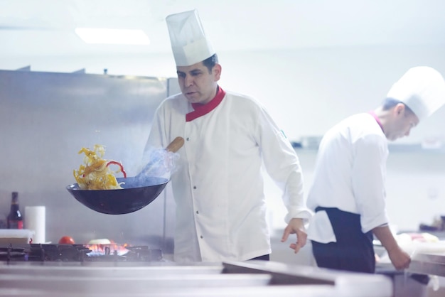 chef en la cocina del hotel prepara comida vegetal con fuego