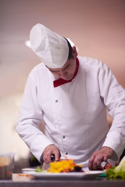 Foto chef en la cocina del hotel preparando y decorando comida, deliciosas verduras y cena de carne