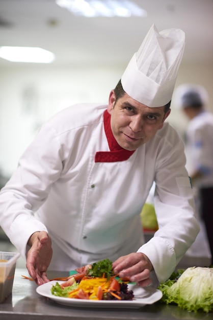 chef en la cocina del hotel preparando y decorando comida, deliciosas verduras y cena de carne