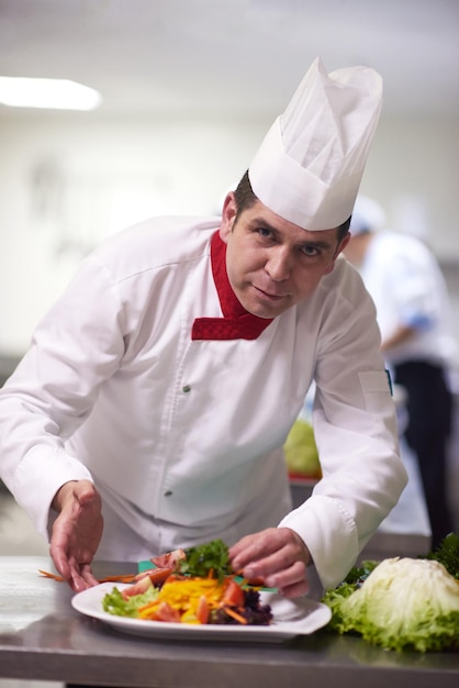 chef en la cocina del hotel preparando y decorando comida, deliciosas verduras y cena de carne