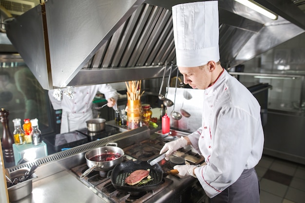 Chef en la cocina del restaurante en la estufa con pan, cocina