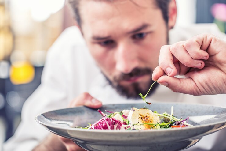 Chef en cocina de restaurante preparando comida ensalada de verduras con queso de cabra y decora la comida