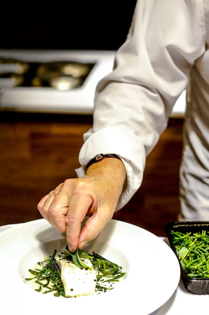 Foto chef cocinando, chef preparando comida, chef decorando un plato en la cocina