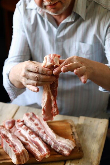 Un chef cocinando costillas de cerdo crudas.