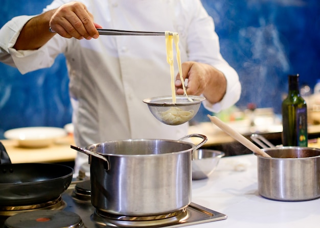 Chef cocinando espaguetis en la cocina