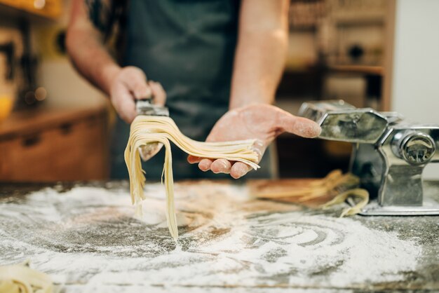 Chef cocinando fettuccine en máquina de pasta