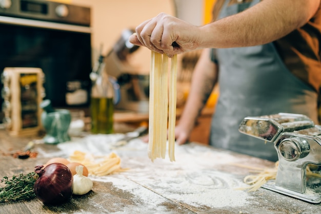 Chef cocinando fettuccine en máquina de pasta