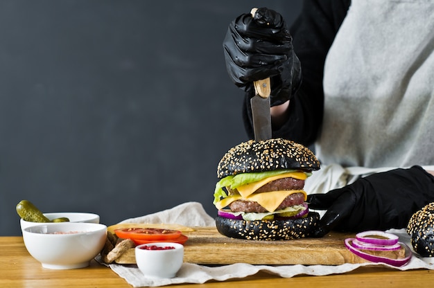 El chef cocinando una jugosa hamburguesa. El concepto de cocinar hamburguesa con queso negro. Receta de hamburguesa casera.