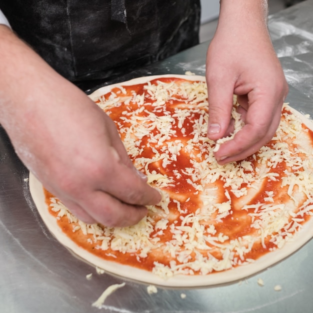 Chef cocinando pizza y agregando queso encima. Comida tradicional italiana sencilla pero deliciosa