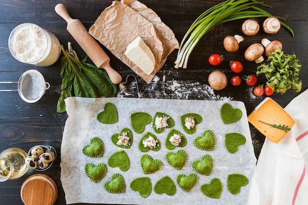 Chef cocinero paso a paso hace ravioles verdes en forma de corazón para una cena festiva