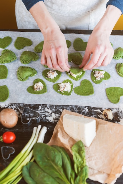 Chef cocinero paso a paso hace ravioles verdes en forma de corazón para una cena festiva