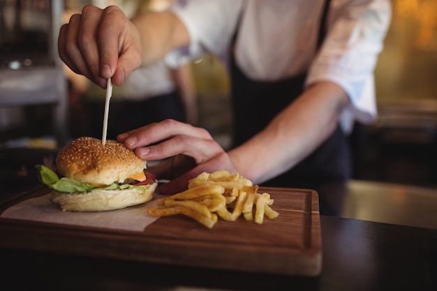 Chef colocando un palillo sobre una hamburguesa en la estación de pedidos