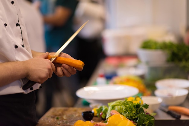 chef com as mãos cortando cenouras em uma mesa de madeira, se preparando para uma refeição no restaurante