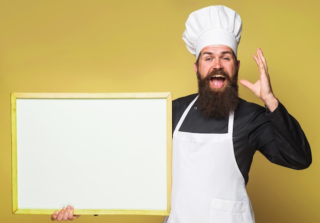 Chef com menu vazio Cozinhar com quadro-negro em branco Padeiro barbudo com placa de publicidade Espaço de cópia