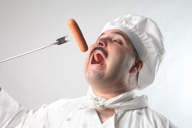 Chef comiendo una salchicha