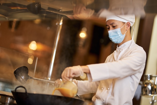 Chef concentrado agregando ingredientes en un wok