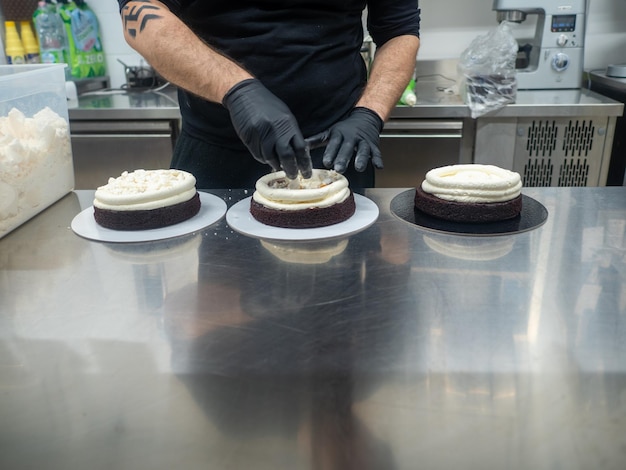 Chef confeiteiro confeccionando um bolo fosco de chocolate amargo com 3 andares recheado com frutas vermelhas e chantilly