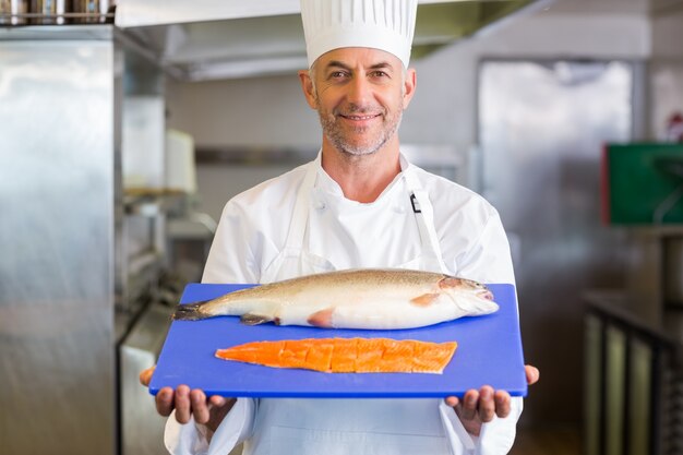 Chef de confianza con bandeja de pescado crudo en la cocina