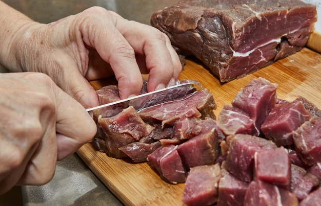 Chef corta a carne bovina em cubos para cozinhar