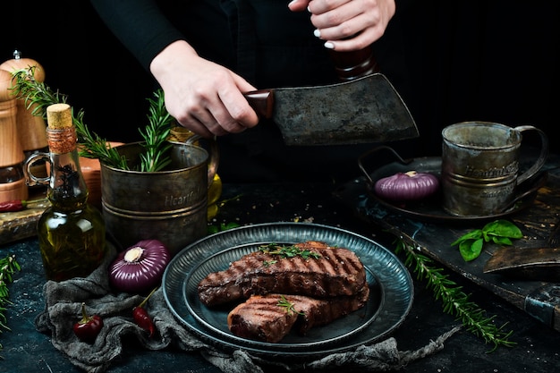 El chef corta el bistec a la parrilla. Sobre un fondo de piedra negra.