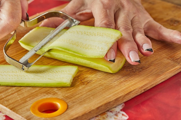 Chef corta calabacines en rodajas en la cocina de casa