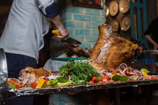 Chef corta carne de cerdo al horno en un restaurante