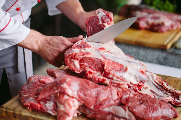 Chef corta carne com uma faca em um restaurante