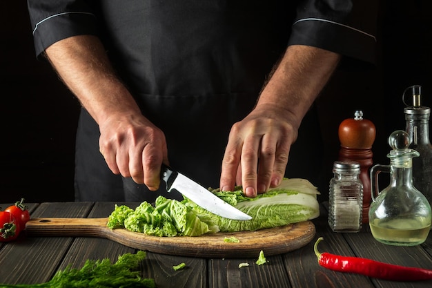 El chef corta la col de Pekín con un cuchillo.