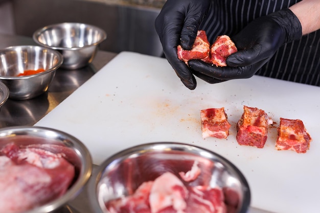 El chef corta costillas de cerdo y las marina en la cocina del restaurante